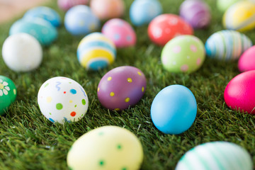 easter, holidays and tradition concept - colored eggs on artificial grass