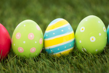 easter, holidays and tradition concept - row of colored eggs on artificial grass