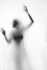 Silhouette of beautiful sexy woman behind curtain on white background