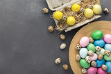 Colored Easter and quail eggs set on black table