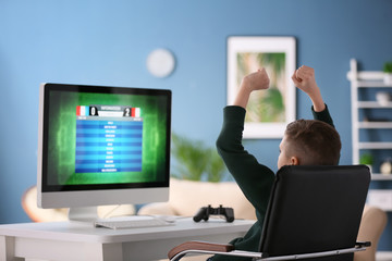 Obraz na płótnie Canvas Emotional little boy playing computer game at home