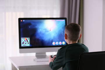 Cute little boy playing computer game at home