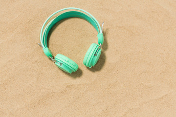 Fototapeta na wymiar music, audio equipment and vacation concept - earphones on summer beach sand