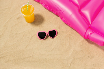 vacation and summer holidays concept - pink sunglasses, orange juice and swimming mattress on beach sand