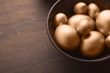 Golden easter eggs in wooden bowl