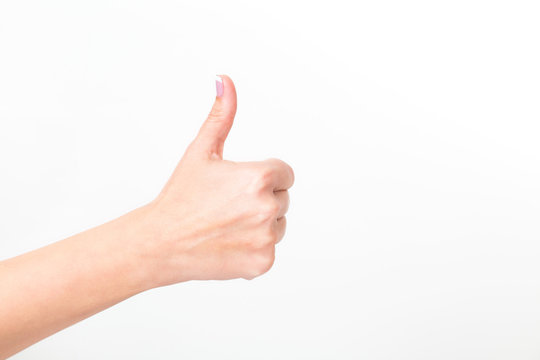 Closeup view of one female hand making like gesture. Woman shows thumb up as sign of success or approval isolated on white background. Horizontal color photography.