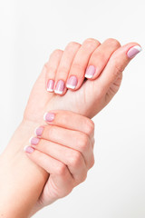 Closeup view of beautiful female hands with fresh professional french pink and white manicure. Perfect as wedding manicure or to spring or summer seasons. Vertical color photography.