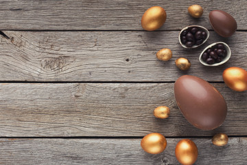 Border of chocolate easter eggs on wooden background