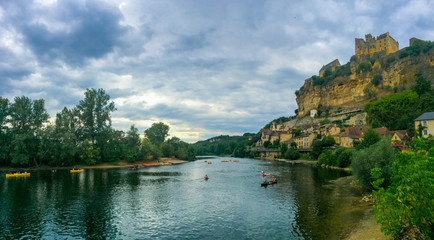 Fototapeta na wymiar Beynac-et-Cazenac, Dordogne / France - August 1, 2015: Kayaks in the Dordogne River and the Castle on the top