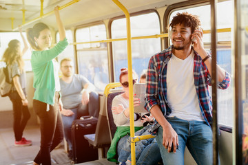 Young modern Afro-American man sitting alone in a public transport and listening to the music....