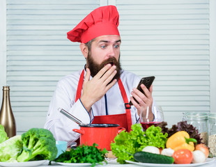 Hipster in hat and apron learning how cook online. Culinary education online. Elearning concept. Man chef searching internet recipe cooking food. Chef smartphone watch culinary show. Culinary school