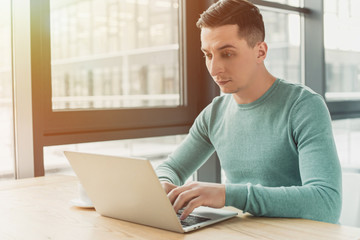Fototapeta premium handsome man typing on laptop while sitting at home