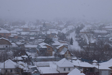 Cloudy snow day over the village. Snowfall, top view