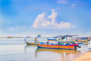 Fototapeta premium Traditional Asian fishing boats with nets parked off the coast before going fishing on a blue sky background with clouds on a sunny morning. Copy space