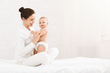 Young mother sitting with baby on bed