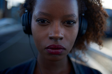 Beautiful black woman wearing headphones in urban city setting during sunrise