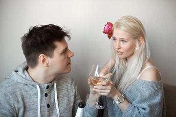 Love is a great feeling. Celebrating anniversary. Young loving couple sitting close to each other hugging and drinking white wine 