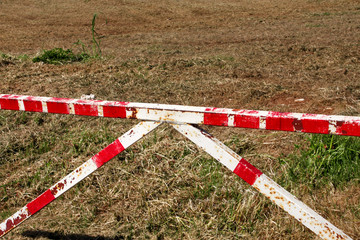 Red and white warning sign barrier on green grass in nature background. Transport, traffic...