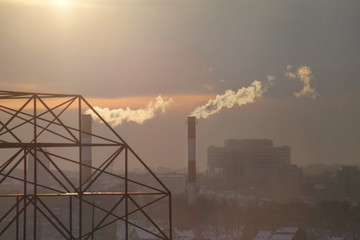 Smoking from industrial chimneys of heating plant emits smoke, smog at sunset in city, pollutants...