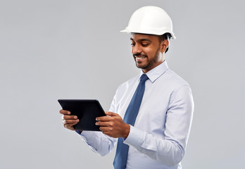 architecture, technology, construction business and building - smiling indian architect or businessman in helmet with tablet computer over grey background