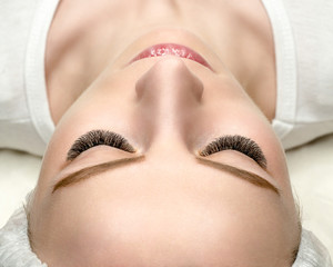 Woman face with eyelash extensions, well groomed skin, top view, close up, selective focus