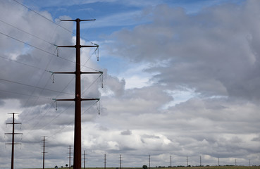 Tall steel electricity pylon and high voltage power lines against a stormy sky in northern Texas, USA.	