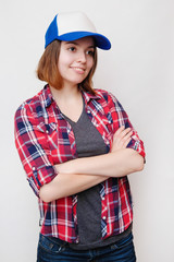 Hipster in a plaid shirt and a cap. Young woman on white background.