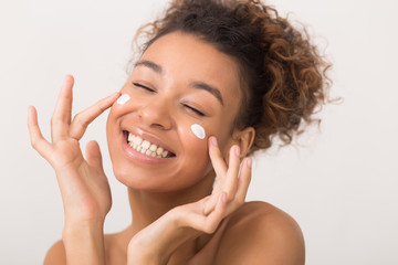 Portrait of laughing woman applying face cream