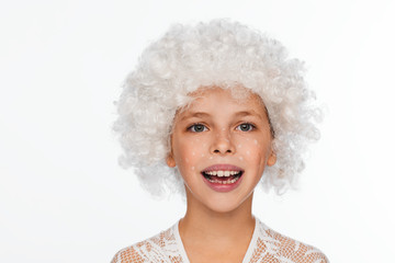 Portrait of a cheerful, energetic eight-year-old girl in a white wig and with white freckles