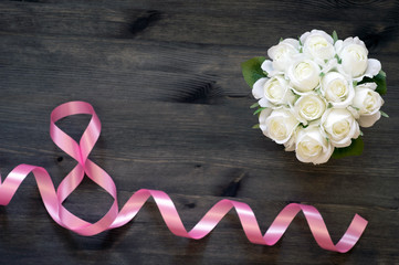 Holiday card March 8 of pink ribbon, a bouquet of white roses on a wooden vintage background