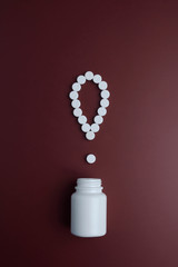 Exclamation mark of white tablets on dark red background. White pills on a red background....