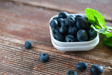 blueberries on a table in a white saucer and in an old cup
