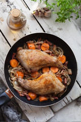 Fried rabbit legs on frying pan with vegetables