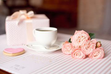 Valentine's day celebration with cup of coffee and valentines decoration on pink tablecloth texture background.