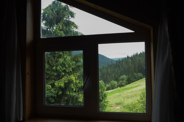 Fototapeta na wymiar Amazing green view through window of wooden rustic house in countryside. Horizontal color photography.