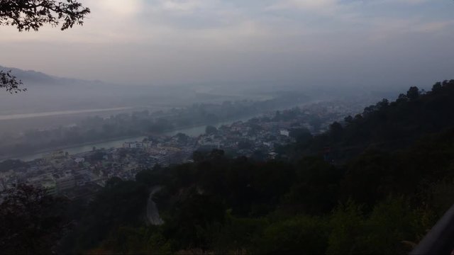 Timelapse of Holy river Ganga flowing in front of mountains and a bridge. Shot at sunriset in Haridwar where pilgrims offers prayers to Goddess Ganga and perform ritualistic bathing.