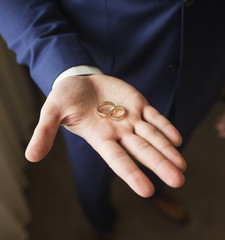 Close up top view of opened palm of man holding two golden wedding rings. Groom or groomsmen ready for wedding ceremony. Color photography.