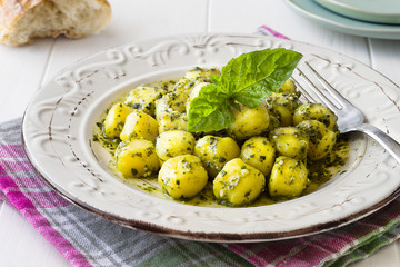 Portion of homemade gnocchi with 'Pesto' sauce on white wooden table