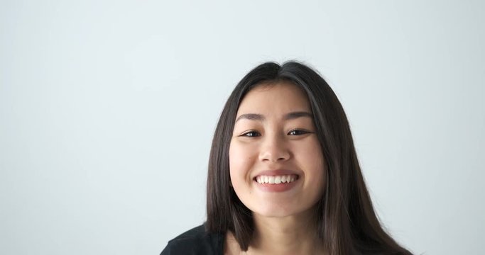 Happy asian woman showing ok gesture with both hands on her eyes