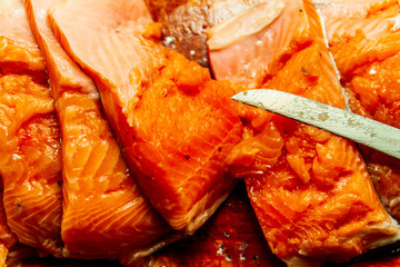 Salmon cuts pieces on a cutting board with a knife isolated 