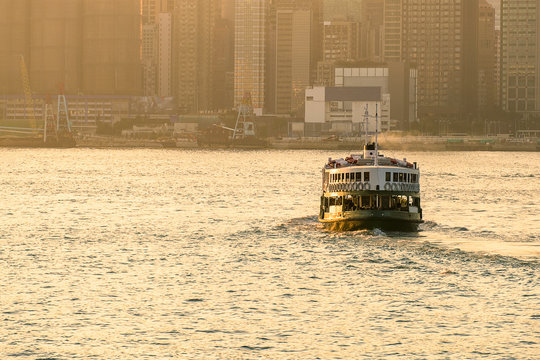 green passenger Ferry in victoria harbour with cityscape background against morining sunrise, services between Kowloon and Hong Kong Island