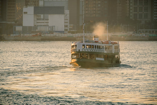 green passenger Ferry in victoria harbour with cityscape background against morining sunrise, services between Kowloon and Hong Kong Island