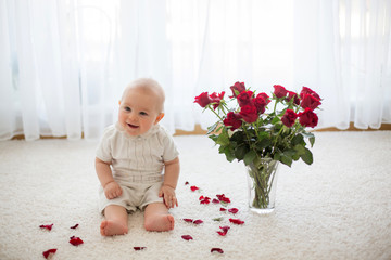 Little cute baby toddler boy, sitting with roses for mom