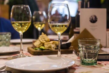 White wine in glasses on a table in a restaurant where a group of friends or family is having dinner