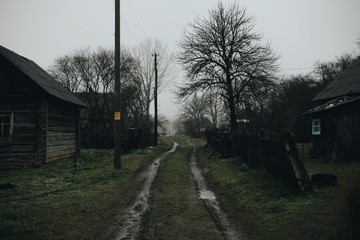 Street in russian village. Wooden old house in spring. Dirty nature around.
