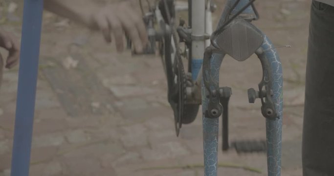 high angle shot of pedals being tested and turned by hand. Father and son repair and maintain a bicycle in a do it yourself manner