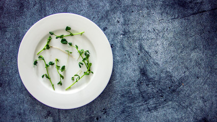 Microgreen on a white plate on a dark background. Background for weight loss, diet, pea sprouts on a white plate