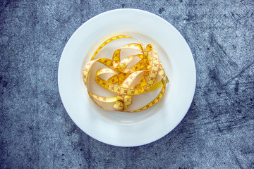 Tape for changing the body on a white plate on a dark background, the background is about losing weight, diet, losing weight