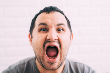 Portrait of young man screaming with beard in grey t-shirt