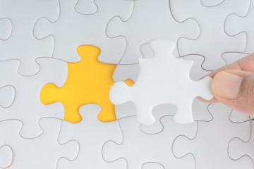 Obraz premium Hand put the last piece of jigsaw puzzle closeup to complete the mission. Selective focus and crop fragment